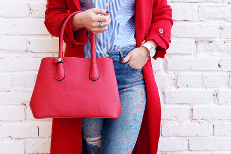 A person holding a rich, red handbag.